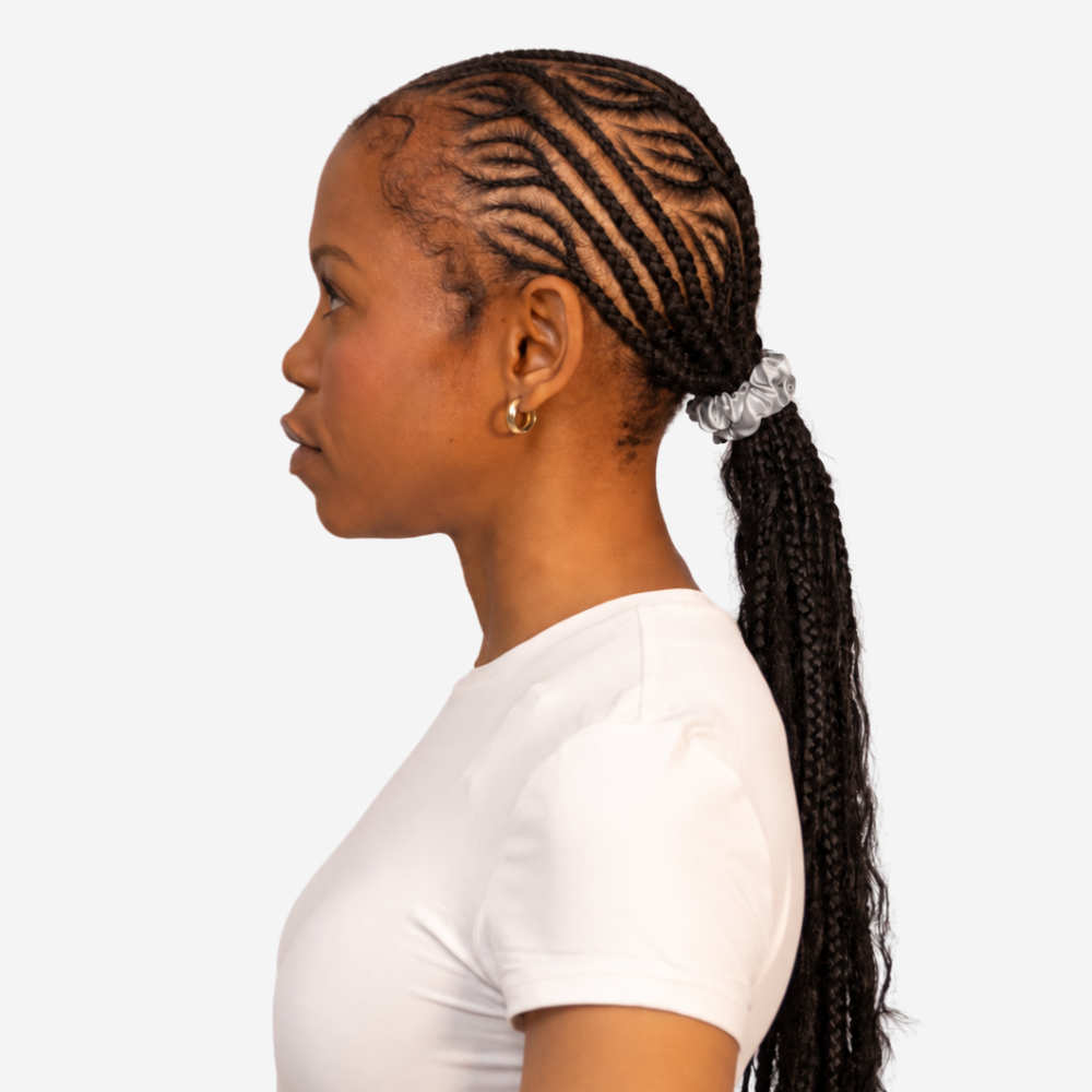 Side profile of a braided ponytail tied with a small silver silk scrunchie