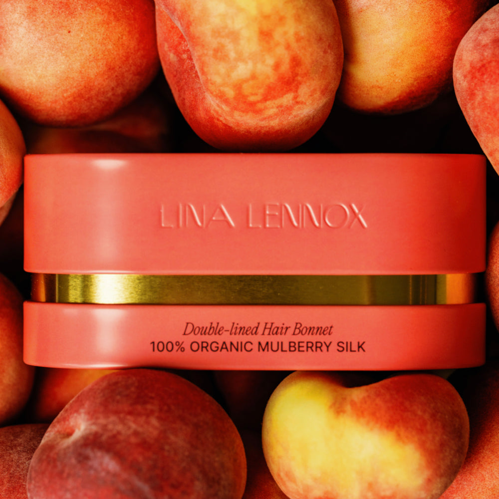 Peachy coral Lina Lennox keepsake case for the double-lined 100% organic mulberry silk hair bonnet, styled with peaches